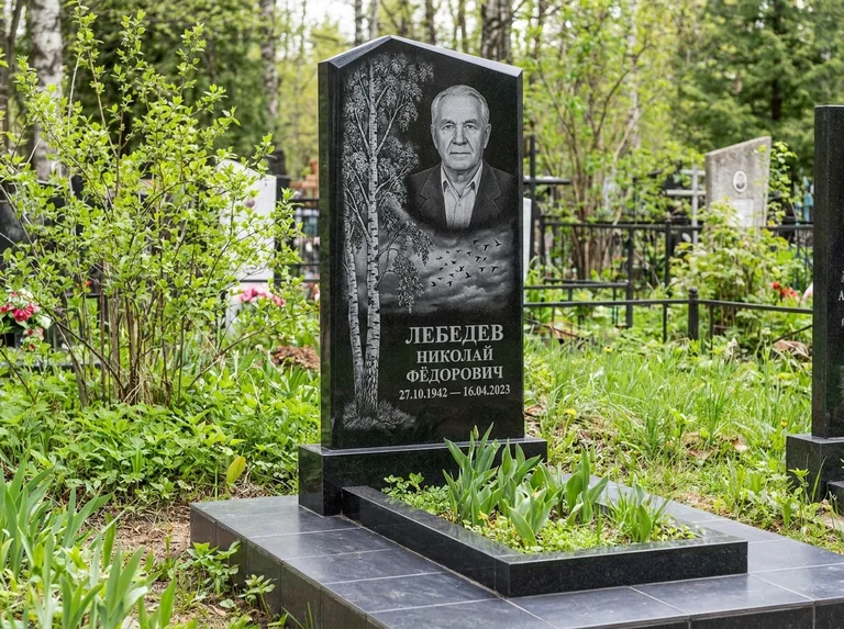 Памятник с гравировкой берёзы: вертикальная стела со скошенным верхом — берёза и стая птиц в небе, гранитный цоколь с тёмной плиткой, работа «Лебедев» во Владивостоке