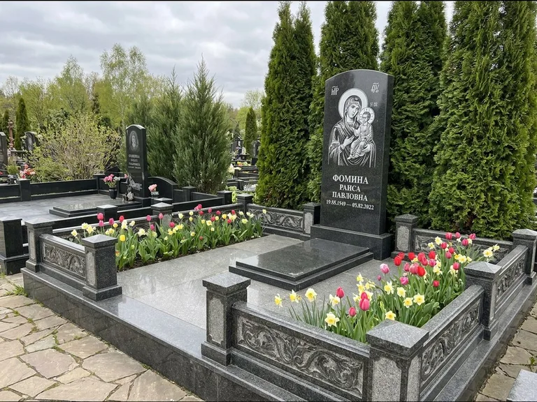 Памятник с гравировкой иконы: высокий гранёный обелиск с крестом-навершием — гравировка образа Матроны Московской, открытый участок без ограды, работа «Третьяков» во Владивостоке