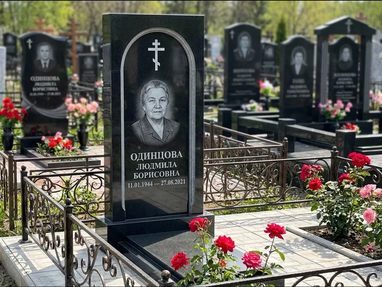 Памятник из чёрного гранита — скромная невысокая стела с крестом с терновым венцом, работа «Лаврентьева» во Владивостоке